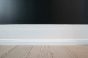 white contemporary baseboard contrasted by a dark blue wall